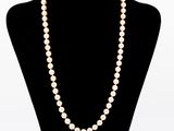 a white pearl necklace on a mannequin with a gold clasp