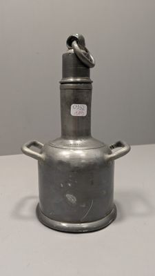 une vieille casserole en métal avec une poignée, posée sur une table blanche