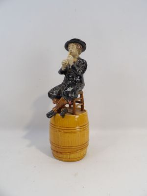 une figurine représentant un homme assis sur un tonneau