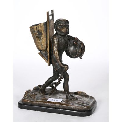 une figurine en bronze représentant un garçon portant un panier et un bouclier