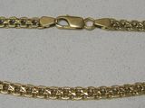 gros plan d'un bracelet en chaîne en or sur une surface blanche