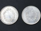 two silver coins sitting side by side on a black surface