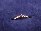 an image of a red and white diamond ring on a blue cloth