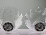 two clear glass vases with black rims sitting on a table