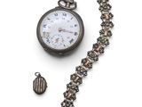 une montre de poche attachée à une chaîne, posée sur une surface blanche