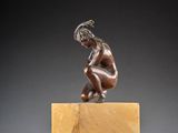 an image of a bronze statue of a man kneeling on top of a marble block
