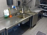 a large stainless steel kitchen with a sink and a refrigerator