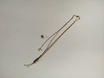un collier en or et une paire de boucles d'oreilles posés sur une surface blanche