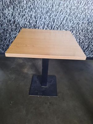 une table en bois avec un piètement en métal noir et un mur orné de motifs en arrière-plan