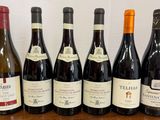 six bouteilles de vin sont alignées sur une table en bois