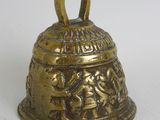 a gold bell with a design on it on a white surface