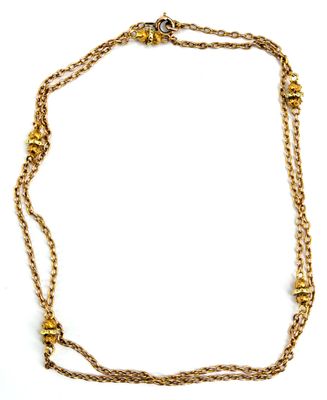 gros plan d'un collier en or avec une chaîne sur fond blanc