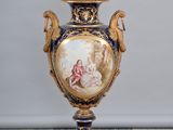 a vase with a painting on it sitting on a pedestal