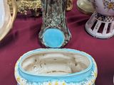 de nombreux vases de toutes sortes posés sur une table, avec une horloge en arrière-plan