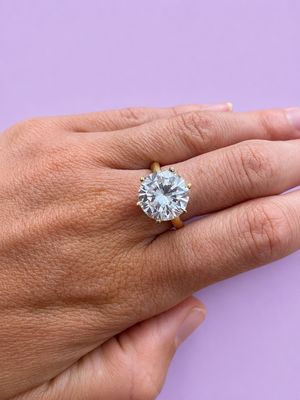 la main d'une femme tenant une bague en diamant sur un fond violet