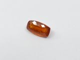 a close up of an orange sapphire stone on a white surface