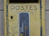 une boîte aux lettres jaune posée contre un mur