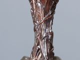 a silver vase that has a bunch of acorns on it