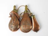 three antique brass bottle ornaments hanging from a rope on a white surface