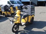 yellow and black scooter parked in a parking lot next to a white van