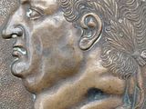 a close up of a bronze medallion with a man ' s face