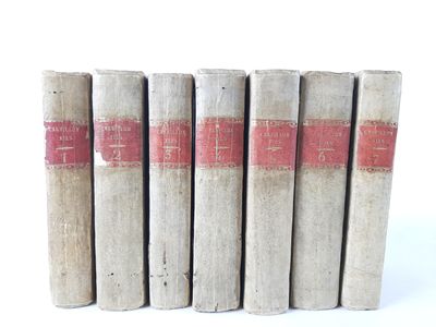 several old books are lined up in a row on a white surface