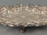 une assiette en argent ornée d'un motif floral sur un fond gris