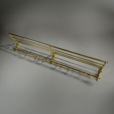 a gold metal shelf with five hooks on it