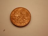 a penny on a white surface with a small insect crawling on it