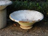 two cement bowls sitting next to each other on the ground