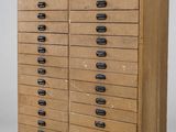 une vieille commode en bois avec de nombreux tiroirs et des poignées noires