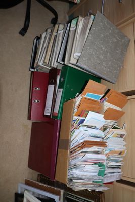 une pile de dossiers et de chemises posée sur une étagère dans un coin de la pièce