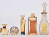 cinq flacons de parfum posés les uns à côté des autres sur une surface blanche
