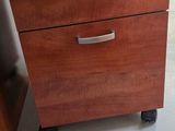 a wooden filing cabinet with three drawers on wheels