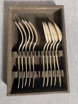 Plusieurs fourchettes et cuillères se trouvent dans une boîte posée sur une table
