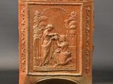 une petite boîte en argile rouge ornée d'un relief représentant un homme et une femme