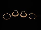 three gold rings and a pair of earrings on a black background