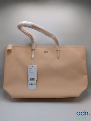 le sac est de couleur beige et porte une étiquette blanche