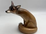 une figurine représentant un chat assis sur une surface blanche