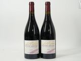two bottles of red wine sitting next to each other on a white surface