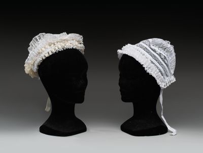 deux têtes de mannequins noires coiffées de chapeaux en dentelle blanche