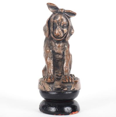 statue of a dog with a bow on its head sitting on a pedestal