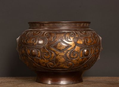 un vase marron posé sur une table sur fond noir