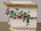 a white vase with flowers painted on it on a table