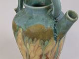 a blue and green vase with a handle on a white surface