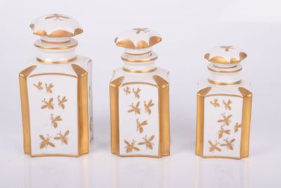 three glass bottles with gold designs on them sitting next to each other