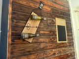 a wooden wall with two wine bottles and a chalk board attached to it
