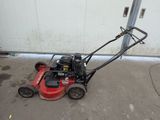 a small red lawn mower parked in front of a garage