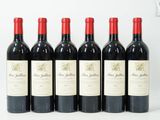 six bouteilles de vin rouge sont alignées sur une surface blanche
