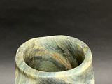 a green marble vase sitting on top of a black table